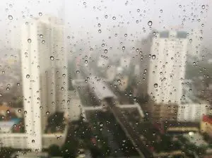 Image of a city from a multistorey building blurred by water droplets and condensation on the window.