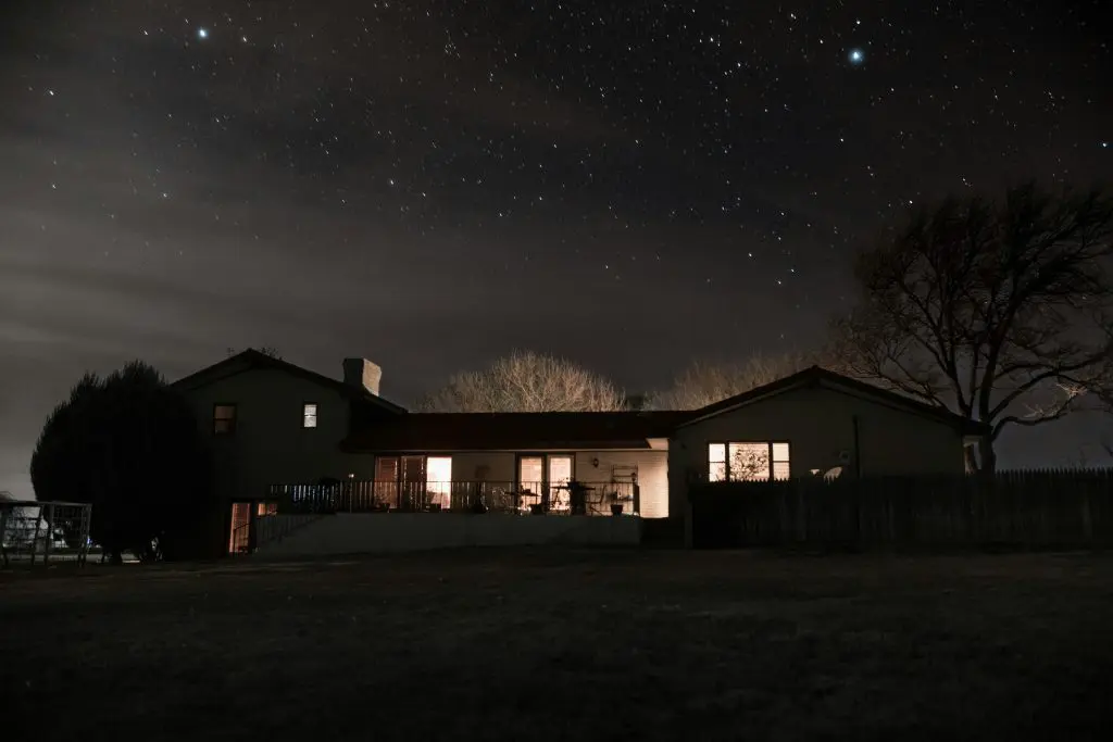 Detached house at night with lights on.
