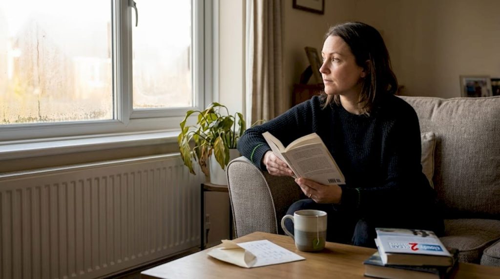 Woman reading near large sunny window