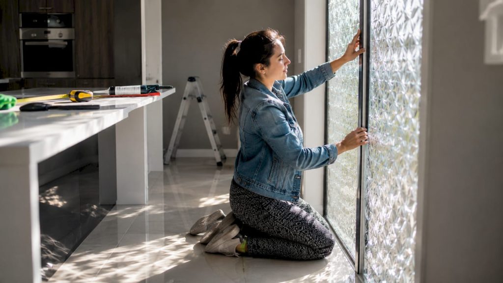Woman installing patterned glass window panel