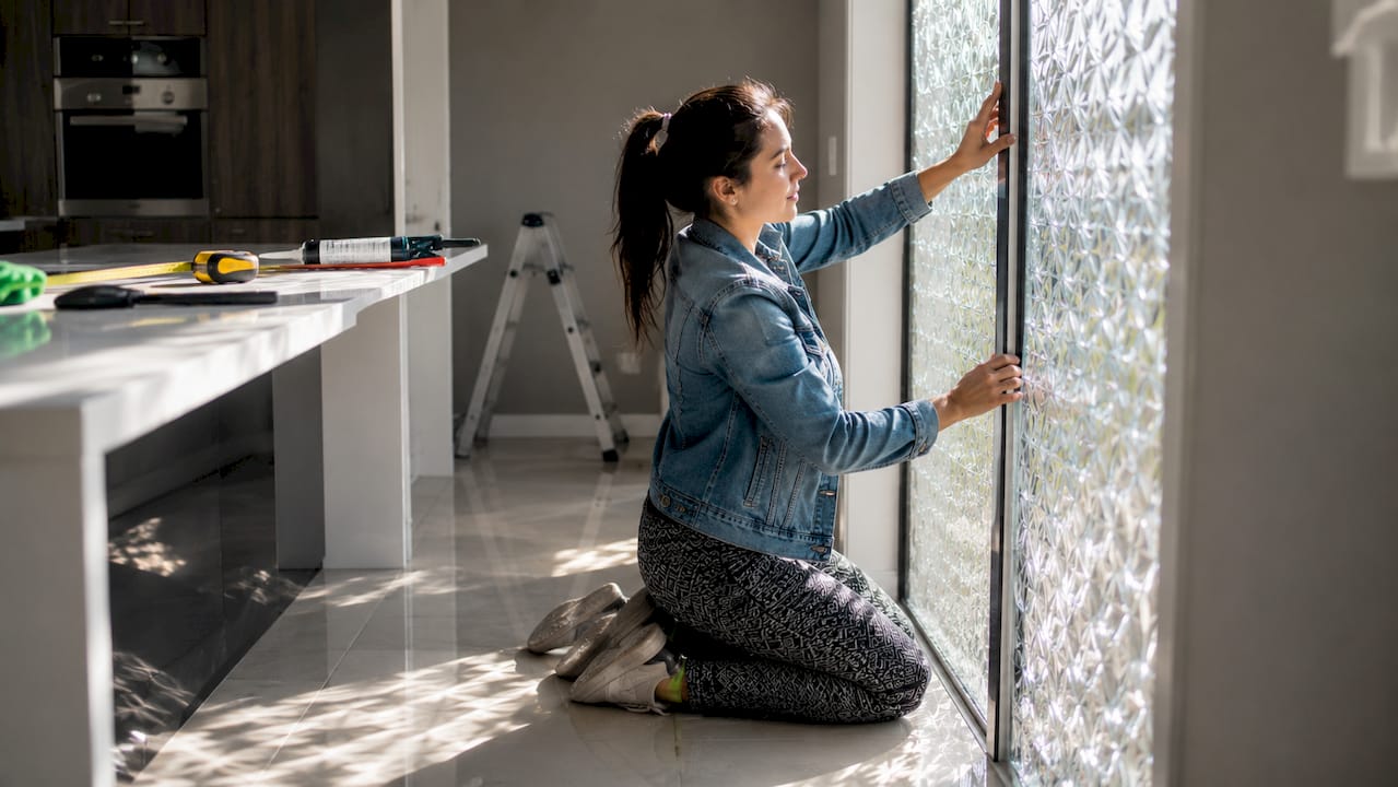 Woman installing patterned glass window panel