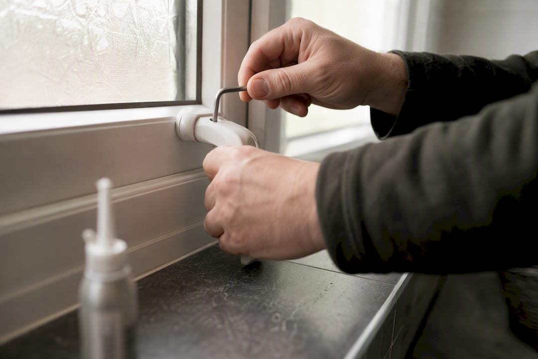 Hands using right-angled tool on uPVC window handle